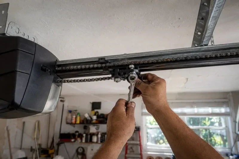 Hands holding a wrench against an opener trolley beneath a chain rail — Chain-Drive Opener Repair, Woolwich